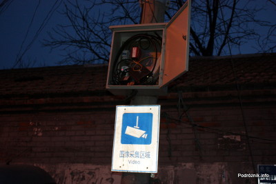 Chiny - Pekin wieczorem - rozbebeszona skrzynka nad znakiem informującym o monitoringu - kwiecień 2013