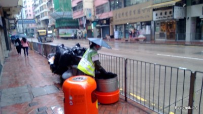 Chiny - Hongkong - pracownik służb miejskich z parasolką na głowie - kwiecień 2013